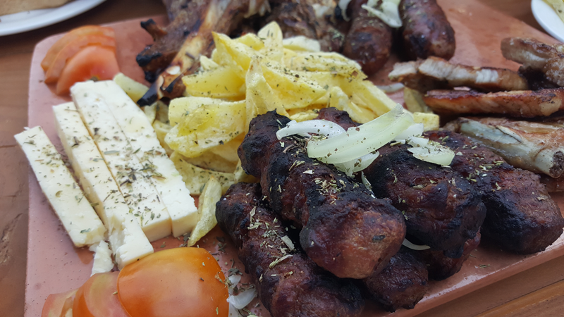 Epifania in montagna in Albania | la carne alla griglia tipica della zona di Korça chiamata Zgara korçare servita con pomodori, formaggio bianco, patate fritte e olive